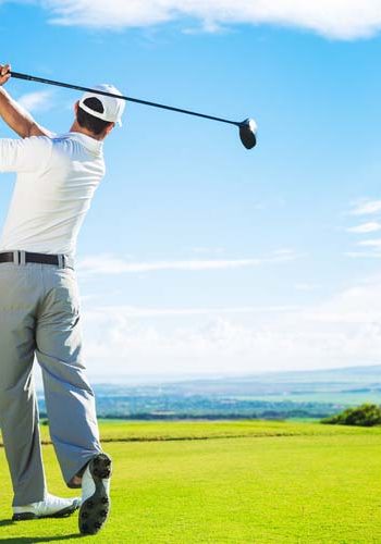 Man Playing Golf on Beautiful Sunny Green Golf Course. Hitting Golf Ball down the Fairway from the Tee with Driver.